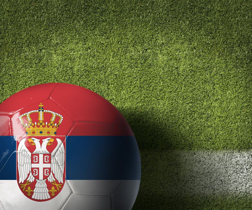 Fudbalska lopta sa zastavom Srbije na travnatom terenu kao simbol domaćih takmičenja